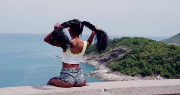 在阳光明媚的夏日里 美丽的女孩观看美丽的大海和小岛的景色的背面 — 图库视频影像