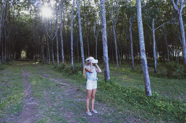 Woman in the forest uses VR virtual reality glasses and is amazed by nature