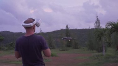 Sanal gerçeklik gözlüklü, dışarıda drone'u kontrol eden bir adam. Tropikal bakış açısında Vr gözlük ve quadrocopter kullanan drone operatörü