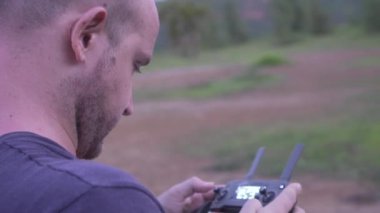 Dışarıda insansız hava aracını kontrol eden adam. Uzaktan kumanda ve akıllı telefon tutan drone operatörü