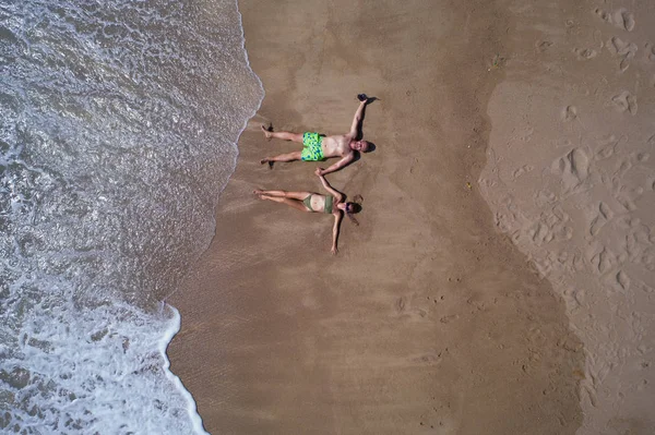 海の近くの砂浜に横たわっている間 手をつないでいるカップルの空中トップビュー 夏休みのコンセプト — ストック写真