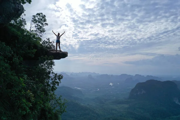 在美丽的绿色山脉和天空背景的岩石边缘的妇女的鸟瞰图 — 图库照片