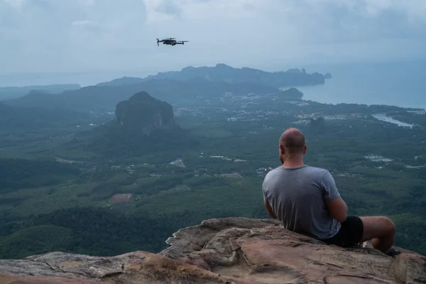 Back View Man Drone Operator Sitting Edge Rock Beautiful Green — Stock Photo, Image