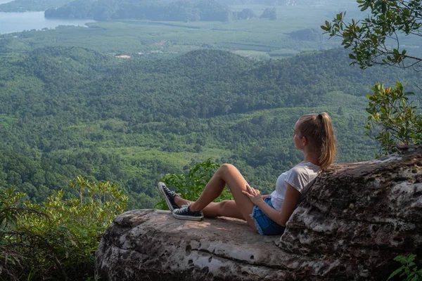 女人坐在悬崖上 看着美丽的风景与山脉和山谷 — 图库照片