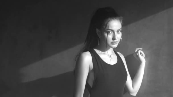 灰色のコンクリートの壁と曇ったスタジオで踊る黒いボディスーツの美しい官能的な女性 スローモーションで黒と白のビデオ — ストック動画