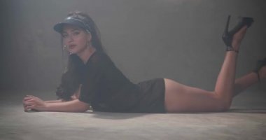 Siyah giyen şehvetli kadın t-shirt, iç çamaşırı ve güneş likörü gri beton duvarlar ile stüdyoda katta dans ile görmek - yavaş hareket video