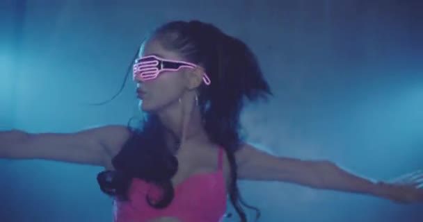 党性感的女人穿着霓虹灯闪烁粉红色胸罩和眼镜跳舞在朦胧的工作室夜总会 — 图库视频影像