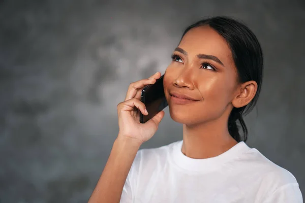 콘크리트 배경을 전화에 말하는 티셔츠에 아름다운 여자의 초상화 — 스톡 사진