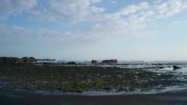 Bali, Endonezya kayalar ile düşük gelgit siyah plaj ve deniz üzerinde uçan hava drone görünümü