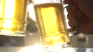 Sıcak yaz gününde güneş ışınları ile taze bira bira bardak bardak clinking Closeup tost - yavaş çekimvideo