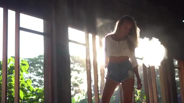 日没の光の背景の上に放棄された建物の中を歩くかわいい女性 スローモーションでビデオ — ストック動画