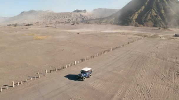 東ジャワ インドネシアの砂漠と美しいブロモ火山でツアージープクルーズの映画撮影空中ドローンビュー — ストック動画