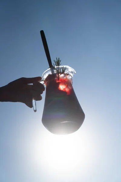 青い夏の空に隔離された水差しの中で赤ワインと一緒にサングリアを提供する手 — ストック写真