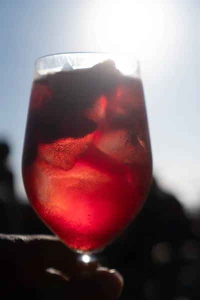 青い夏の空に隔離されたグラスに赤ワインを入れたサングリアの手 — ストック写真