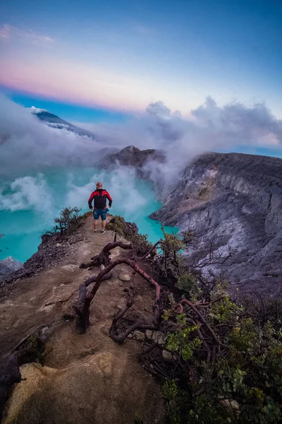 人类旅行者站在火山口的边缘 天空五颜六色 美丽的伊延火山 酸湖和硫磺气体从火山口 印度尼西亚 — 图库照片