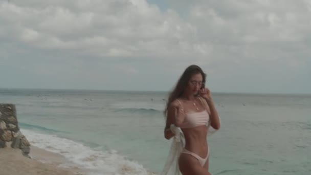 美丽的晒黑的健身女人在比基尼摆姿势的摄影师在海滩上 — 图库视频影像