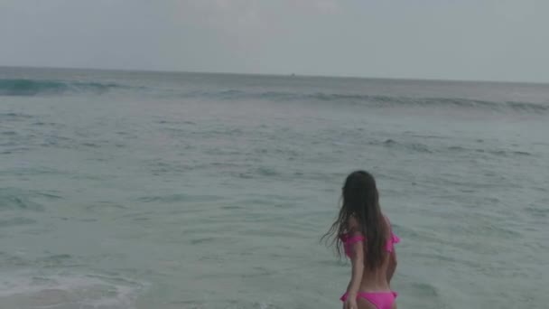 美丽的晒黑健身女人在粉红色比基尼玩 花空闲时间在海滩 视频在慢动作 — 图库视频影像