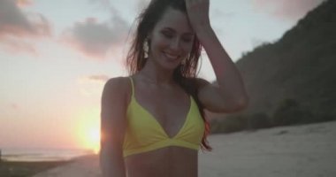 Gün batımında plajda sarı bikini güzel tabaklanmış uygun mutlu kadın - yavaş hareket video