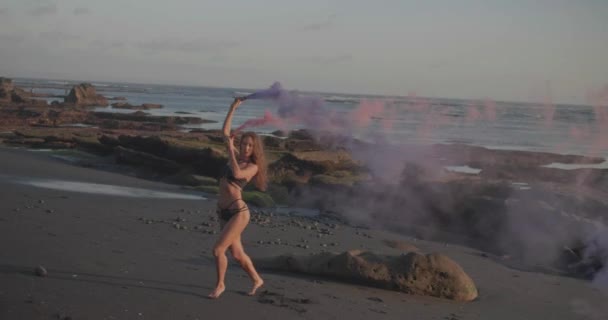 Mooie Vrouw Bikini Dansen Met Gekleurde Rook Het Zwarte Zandstrand — Stockvideo