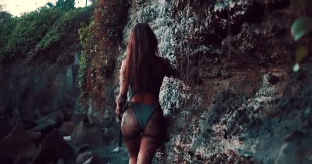 金色落日时 穿着闪亮泳衣的美丽性感女子在黑色沙滩上的小瀑布下洗澡 慢镜头 — 图库视频影像