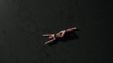 Siyah pırıl pırıl kum plajda poz bikini güzel şehvetli kadın Top havadan drone görünümü