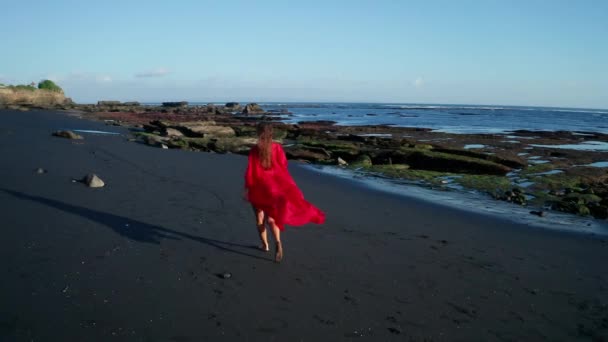 Vzdušný pohled na krásnou smyslnou ženu v bikinách a rudé celkové póze na černém třpytivém písečném pobřeží