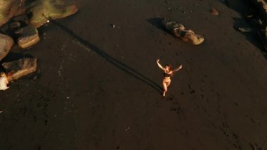 Siyah pırıl pırıl kum plajda poz bikini güzel şehvetli kadın Top havadan drone görünümü