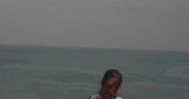 Genç çekici kadın gün doğumunda deniz kıyısında uçurumda direnç güç bandı ile egzersiz - yavaş hareket video