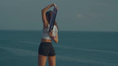 Gün doğumunda deniz kıyısındaki kayalıkta direniş gücü bandı ile egzersiz genç çekici kadın geri görünümü 