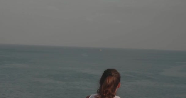 日の出時に海岸の崖で抵抗力バンドで運動する若い魅力的な女性 スローモーションのビデオ — ストック動画