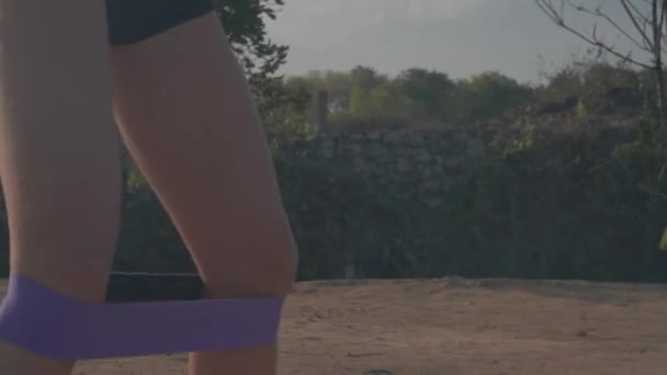 年轻迷人的女人在日出时在海边悬崖上与阻力力量带运动 — 图库视频影像