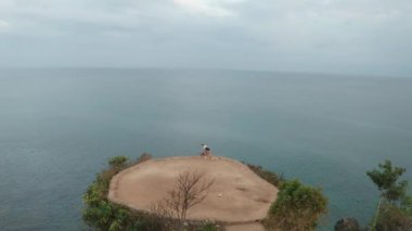 Gün doğumunda deniz kıyısındaki kayalıkta egzersiz genç çekici kadın havadan drone görünümü