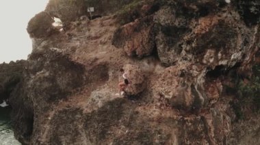 Sabahtan sonra deniz kıyısında güneş doğarken koşuya çıkan çekici genç bir kadının hava aracı görüntüsü.