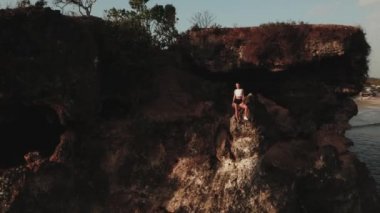 Sabahtan sonra deniz kıyısında güneş doğarken koşuya çıkan çekici genç bir kadının hava aracı görüntüsü.