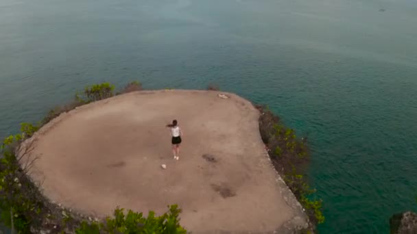 日出时在海边悬崖上慢跑的年轻迷人女人的空中无人机视图 — 图库视频影像