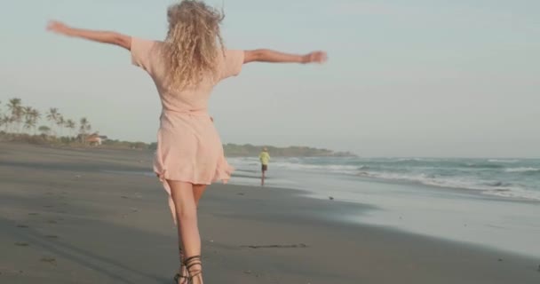 在阳光明媚的夏日 在沙滩上放松的漂亮快乐女孩的背面视图 慢动作视频 — 图库视频影像