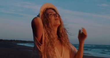 Güzel yaz günbatımı sırasında tropikal plajda rahatlatıcı elbise ve şapka Pretty mutlu kız - yavaş hareket video