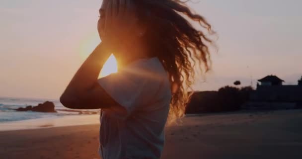 相当快乐的女孩在礼服放松在热带海滩在美丽的夏季日落 视频在慢动作 — 图库视频影像