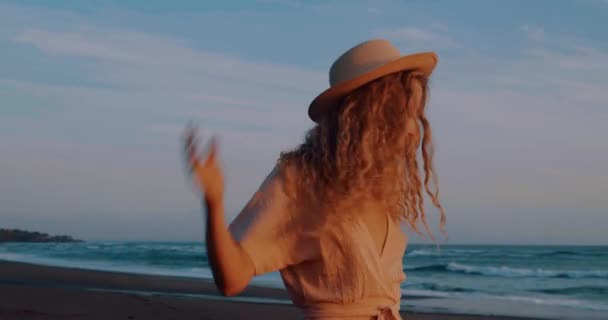 아름다운 해변에서 드레스와 모자에 행복한 소녀의 초상화 슬로우 비디오 — 비디오