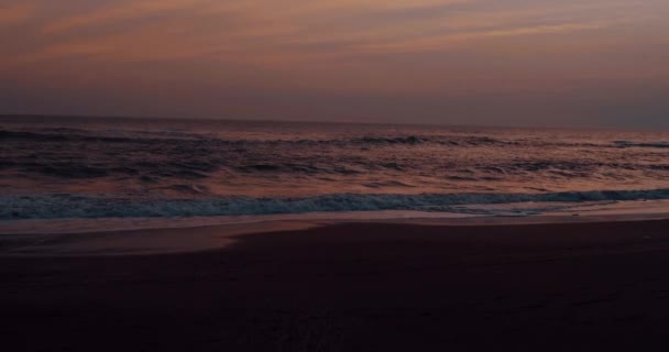 美しい夕日に黒い砂浜と海水 スローモーションでビデオ — ストック動画