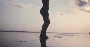 Siyah kum plajda poz siyah elbise ve çizmeler şehvetli esmer kız Kırpılmış görüntü vücut - yavaş hareket video