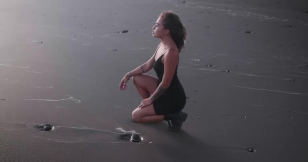 Chica Morena Sensual Vestido Negro Botas Posando Playa Arena Negra — Vídeos de Stock