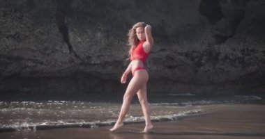 Kırmızı bikini ve üst siyah kum plajda poz şehvetli esmer kız - yavaş hareket video
