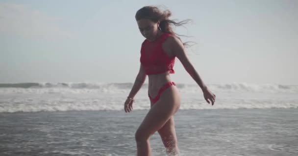 性感的黑发女孩在红色比基尼和顶部在海滩上摆姿势 视频在慢动作 — 图库视频影像