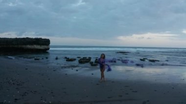 Gün batımında siyah kum plajda renkli duman ile poz mor bodysuit şehvetli esmer kız