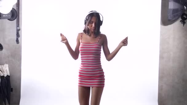 Szczęśliwy Młody Asian Dziewczyna Sukienka Słuchawki Taniec Przez Biały Ściana — Wideo stockowe