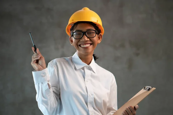 Porträt Einer Lächelnden Attraktiven Asiatischen Ingenieurin Mit Klemmbrett Über Betonwandhintergrund — Stockfoto