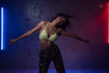 Neon ışıkları ile stüdyoda dans şık giysiler giyen genç güzel moda Asyalı kız dansçı