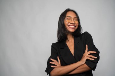 Zarif siyah blazer ve gözlük açık gri duvar arka plan üzerinde poz çekici genç Asya gülümseyen kadın Portresi. Kopya alanı yla alay edin