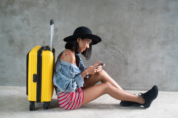 微笑的亚洲年轻女子与行李和手机隔离在混凝土墙上的肖像 人的生活方式 旅游理念 — 图库照片
